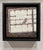 This mixed media work features a solitary burrowing owl perched within a grid-like window frame, creating a sense of...