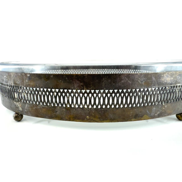 This vintage silverplate casserole holder features an elegant pierced gallery design, curved side handles, and ball feet...