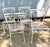 This is a vintage mid-century white wrought iron patio dining chair featuring an ornate scrollwork backrest and a blue...