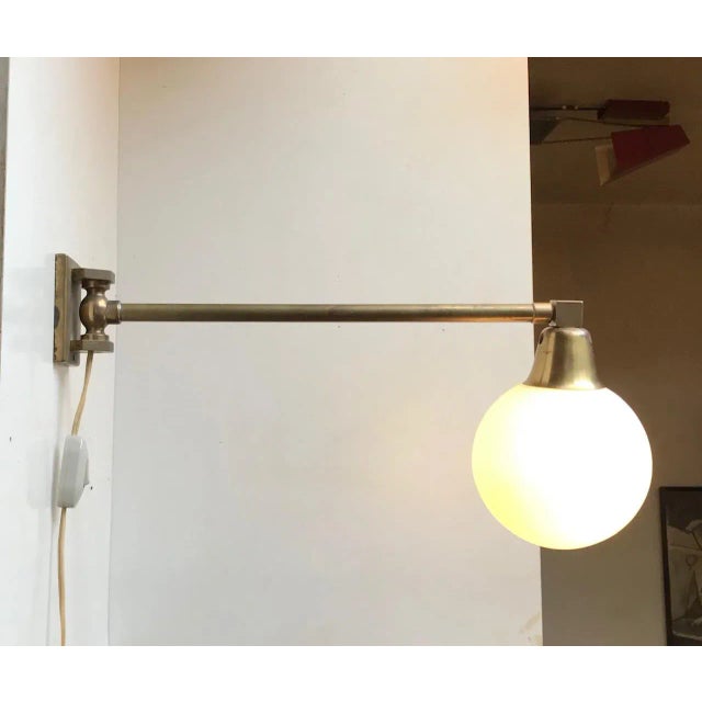 Side to side adjustable wall lamp composed of a solid heavy stock brass 'body' installed with a opaline ball shade. It was...