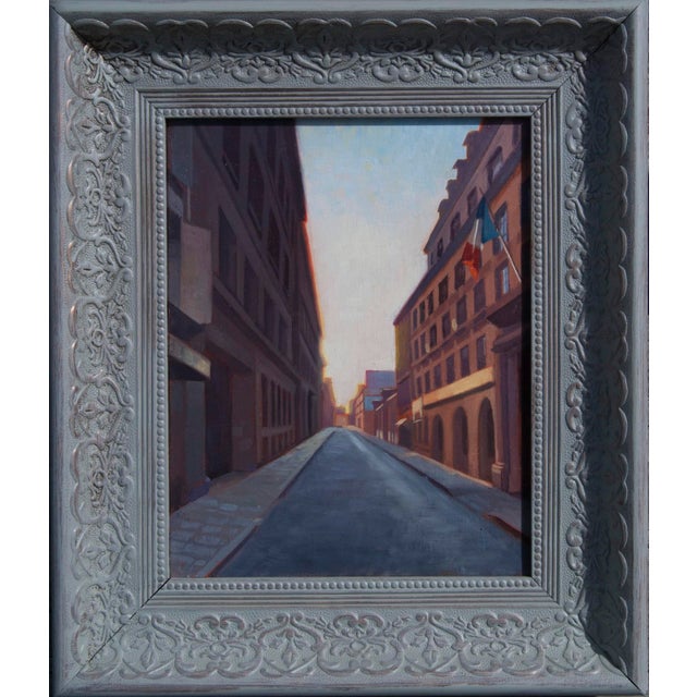 This oil on canvas depicts a quiet Parisian street bathed in the warm glow of early morning light, with shadows stretching...