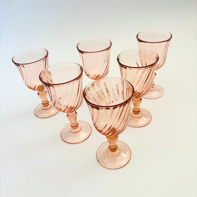 A set of 6 vintage wine glasses in a pale blush pink hue. Each glass has a lovely swirl design. Made in France by Arcoroc....