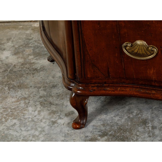 An Italian walnut commode from the early 19th century, with three drawers, serpentine front and bronze hardware. Created...