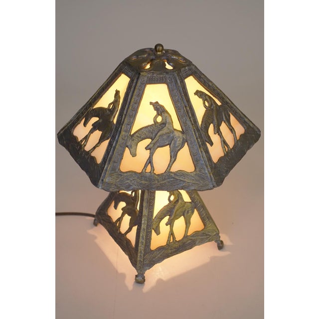 A dramatic and sculptural Mission style shaped form Native American Indian "End of the Trail" panel relief slag glass lamp...