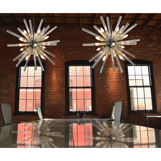 Sputnik chandelier with 30 crystal glass 'triedri' prisms radiating from a centre black metal nucleus. Brass lamp holder....