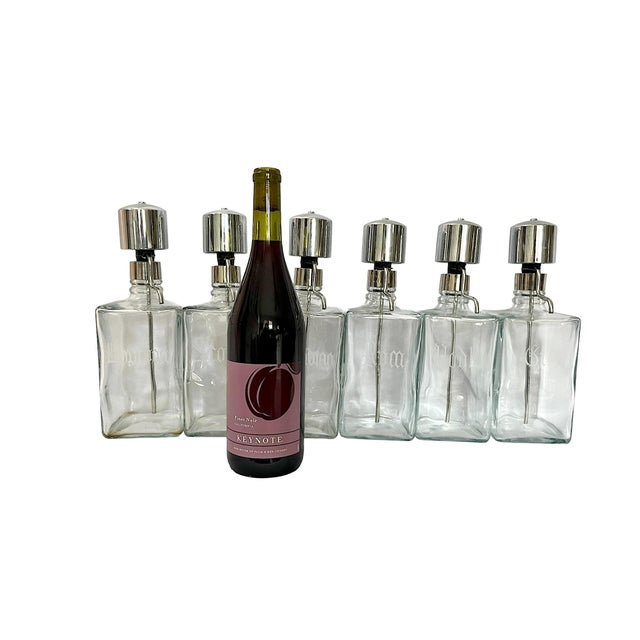 A striking and increasingly hard-to-find set of six vintage glass liquor dispensers with polished chrome pour tops and...