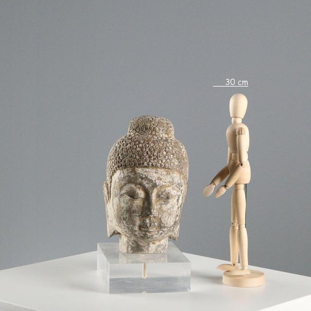 Stone sculpture depicting the head of Buddha with a acrylic glass support. This piece is attributed to the mentioned...