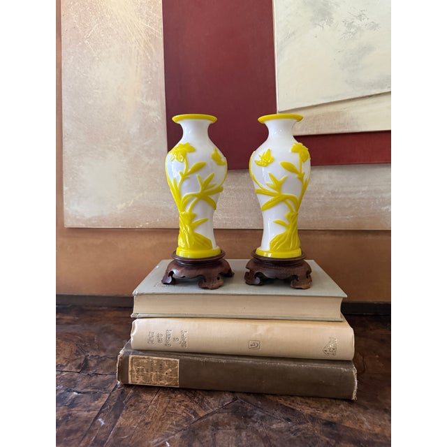 A striking pair of mid-century Chinese Peking glass vases featuring vibrant yellow overlay decoration carved against an...