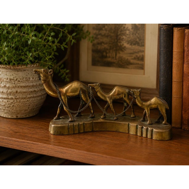 Bring a touch of vintage global charm to your home with this striking brass camel caravan sculpture featuring three camels...