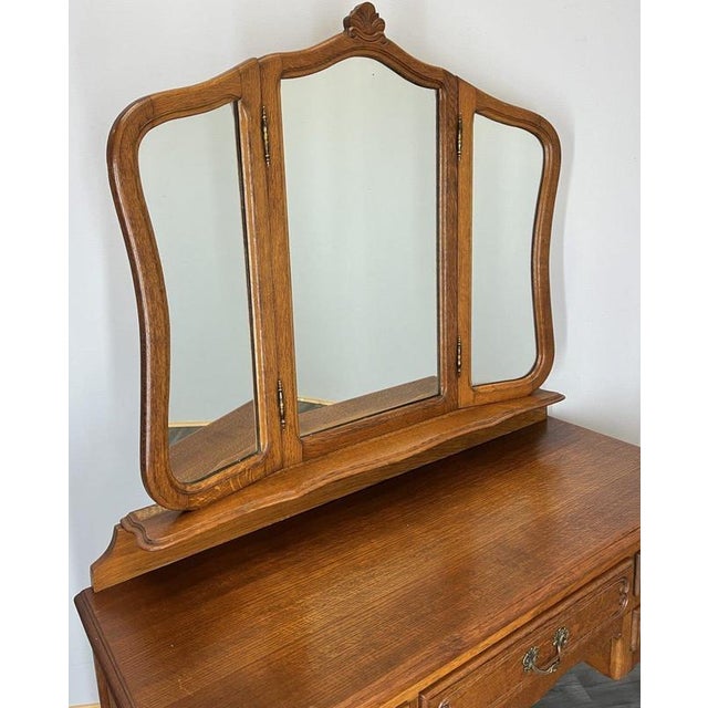 A charming Vintage French Louis dressing table crafted in warm oak, featuring flowing carved lines, ornate handles and a...