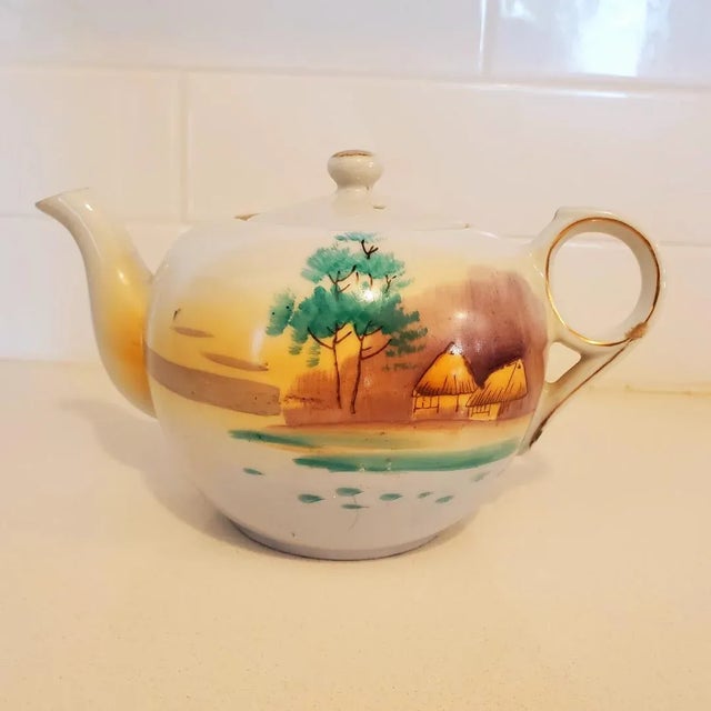 Lovely vintage teapot with handpainted trees and huts. Gold trim on spout, handle and rim. In very good condition...