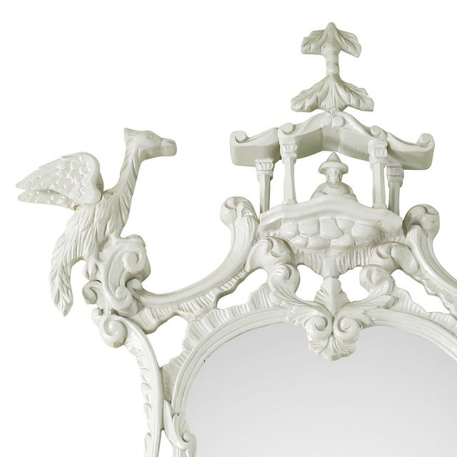 A Chinoiserie style carved mirror featuring an elaborately sculpted pagoda crest flanked by a pair of finely detailed...