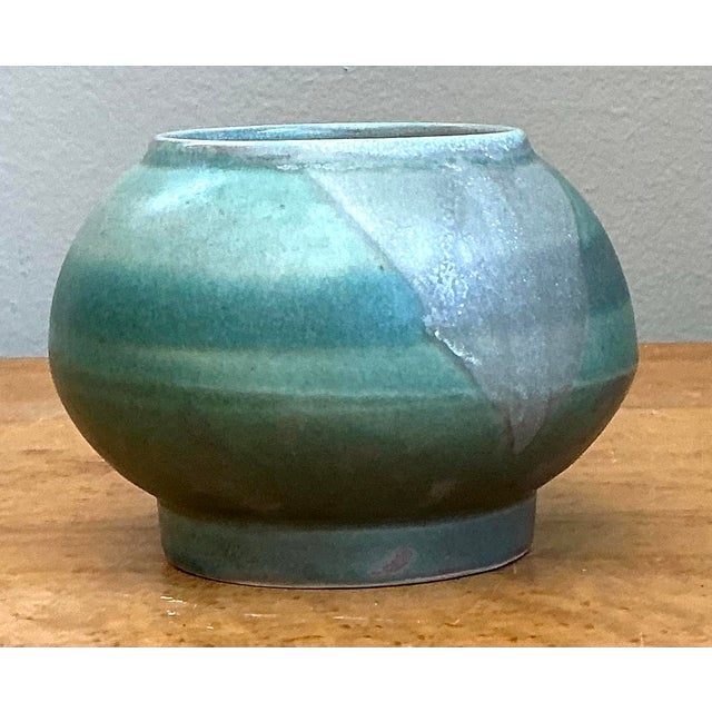 This captivating studio pottery vessel presents a sophisticated fusion of organic form and contemporary glaze work. Hand-...