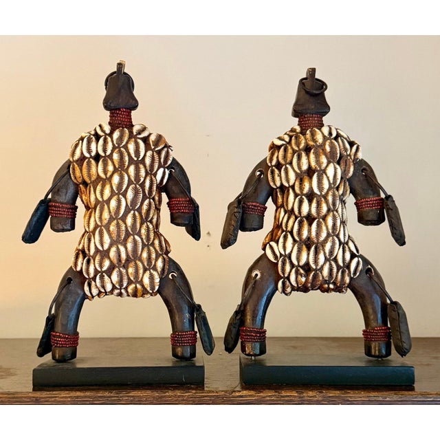 A striking matched pair of traditional African fertility dolls, carved in dark wood and densely sheathed in overlapping...