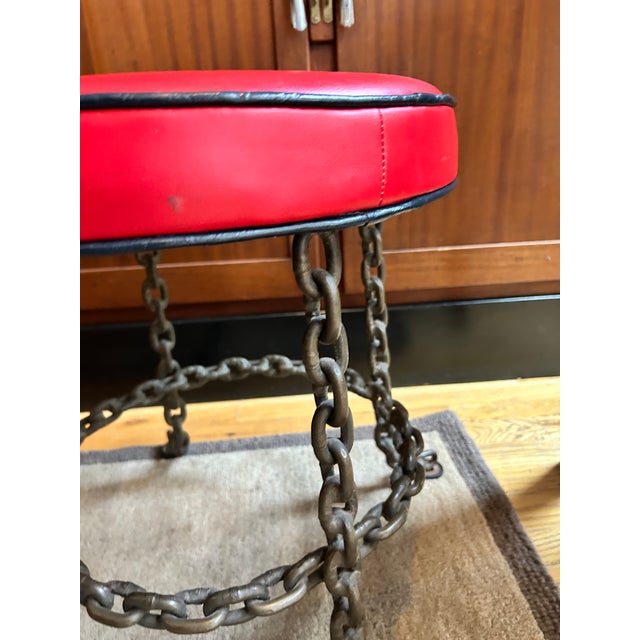 A sculptural accent stool containing heavy welded iron chain links. The base has a beautiful aged patina consistent with...
