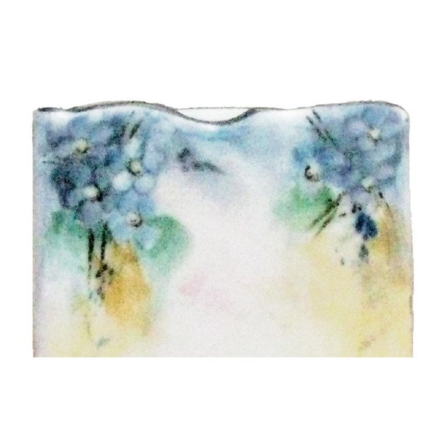 Lovely hand painted porcelain match box keeper / match strike with attached ashtray. Beautiful floral sprays adorn the...