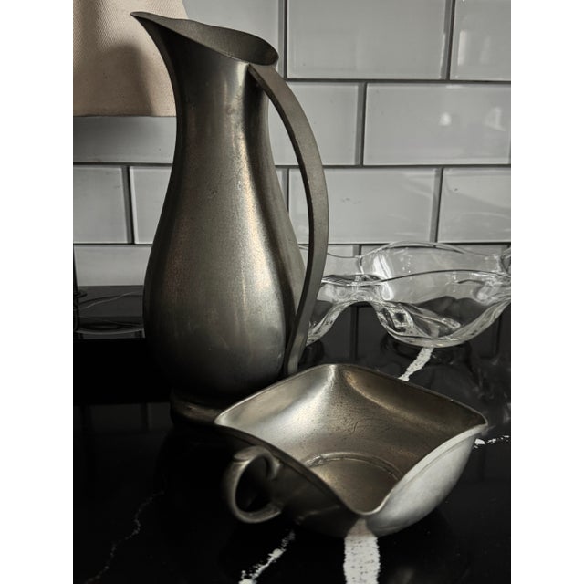A refined mid-century sculptural pewter pitcher with original matching basin, handmade in Holland and bearing its original...