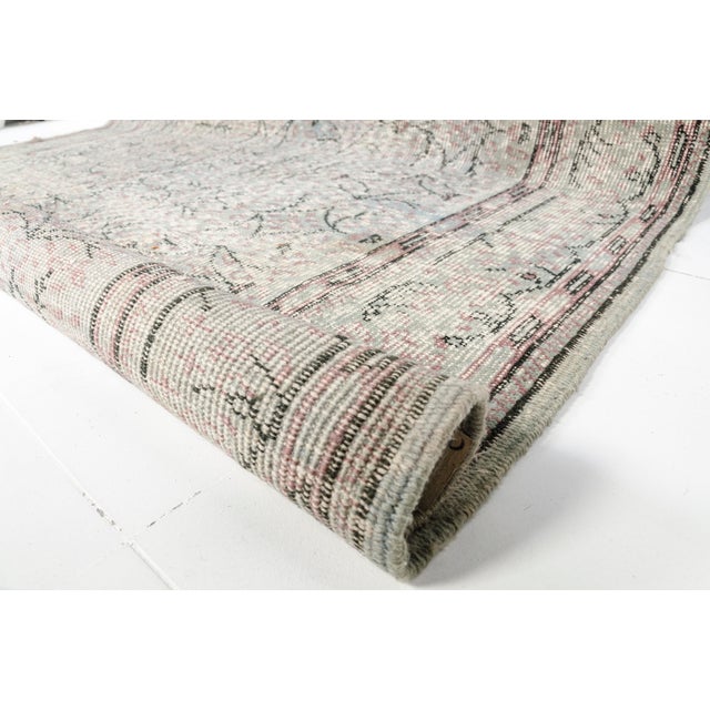 This is a vintage Turkish Oushak rug from the Mid 20th Century. The piece was hand-knotted.