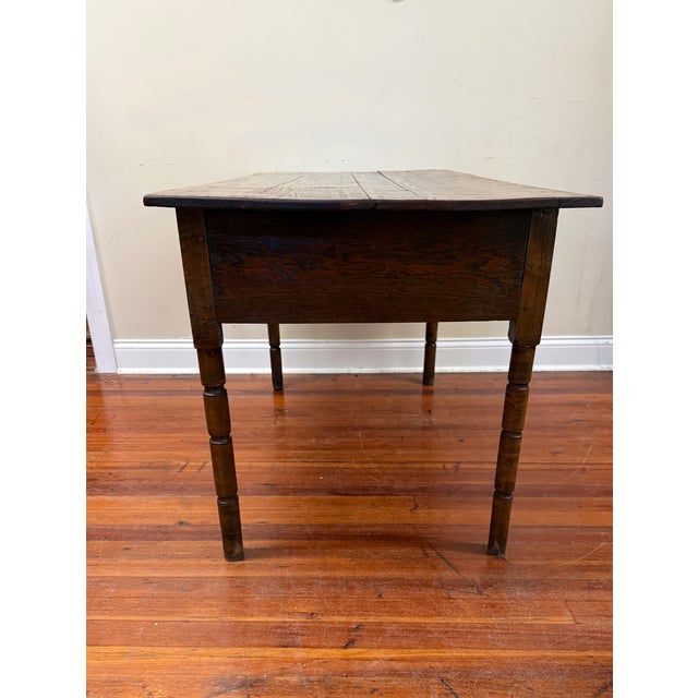This antique table appears to be a 19th-century primitive huntboard or tavern table featuring a two-board top which has...