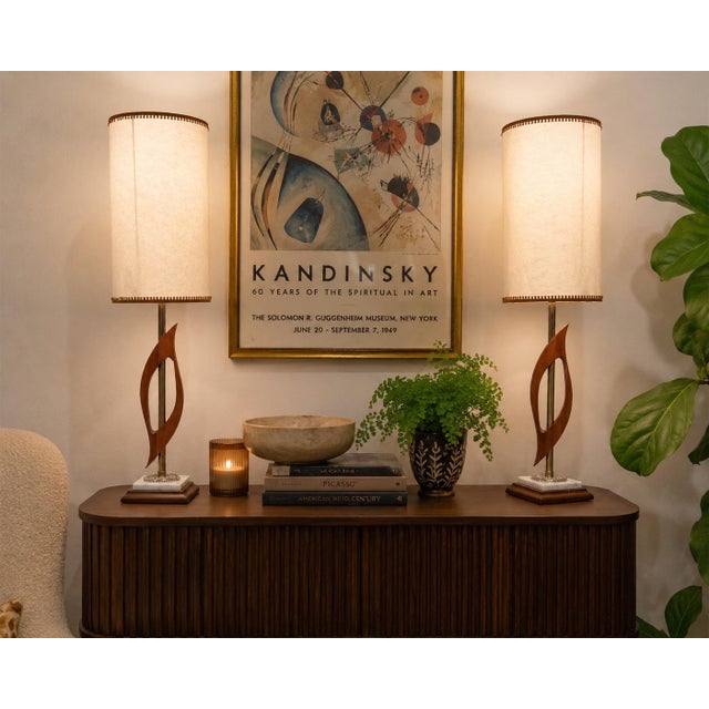 Exceptional pair of Mid-Century Modern table lamps featuring sculptural walnut bodies, polished brass accents, and elegant...