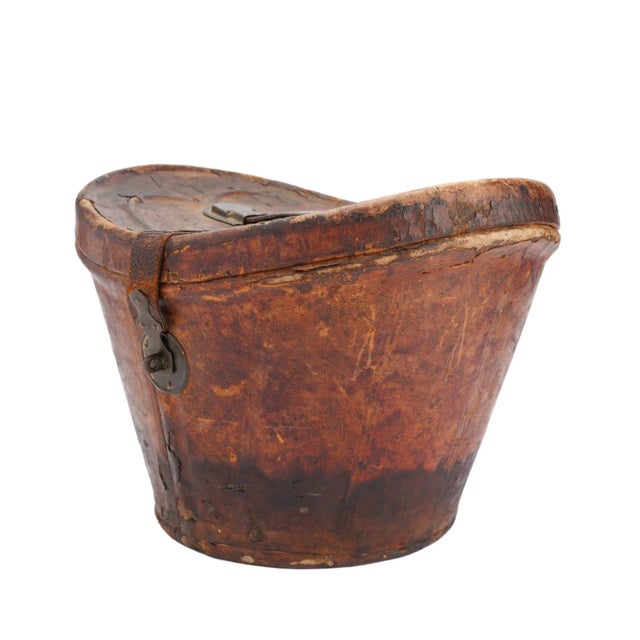 Distressed leather hat box for a man’s wide brim top hat. The lid is hinged and has a metal closure. The handle and strap...