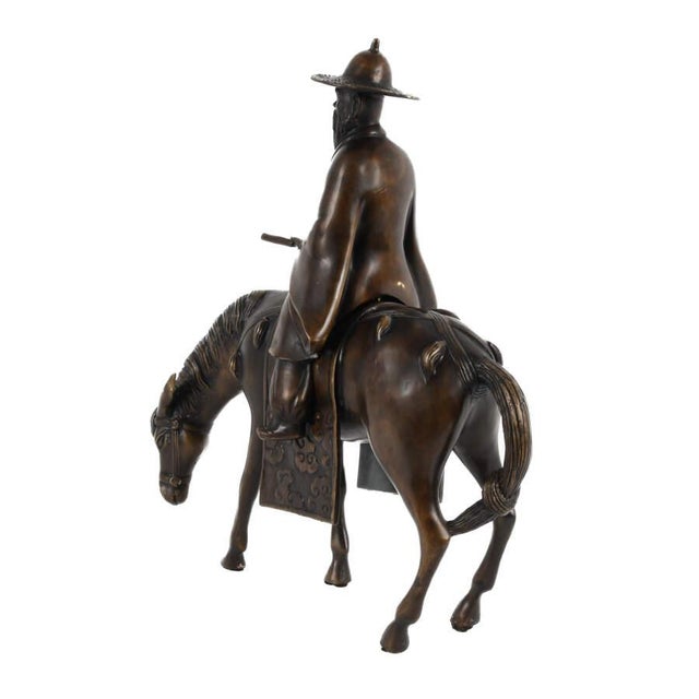 This Chinese bronze sculpture depicts a rider seated atop a horse in a quiet, naturalistic pose, offering a refined...