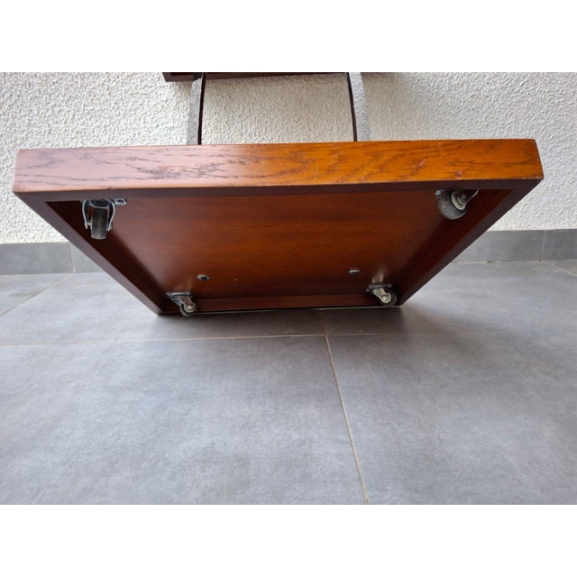 The table features a veneered wood top and base, connected by attractive chrome brackets and practical wheels for easy...