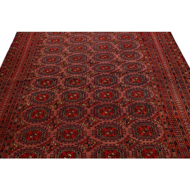 Beautiful vintage Turkmen hand-knotted wool rug with a terracotta field. This Persian rug has navy blue and red accents in...