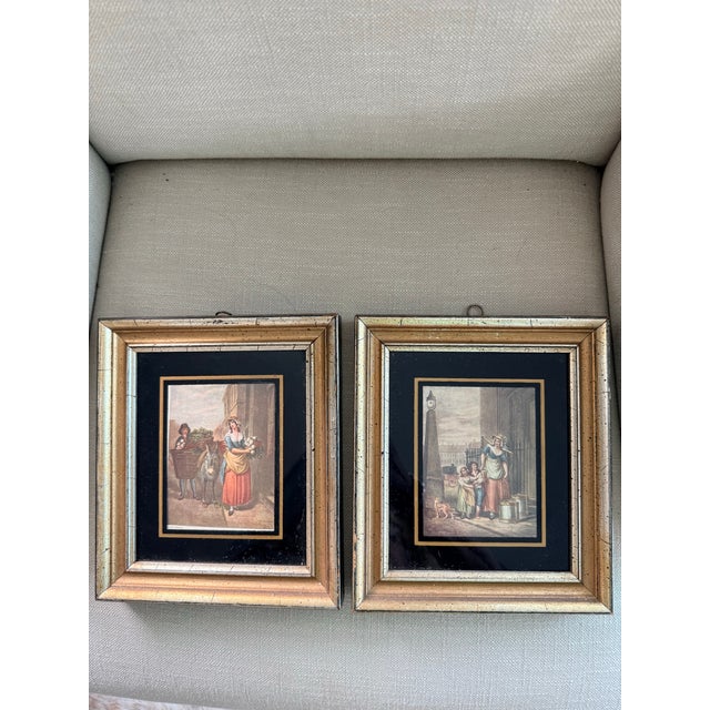 Framed lithographs with black mats and silver/ gold frames. One picture is of a milk maid delivering milk and the other is...