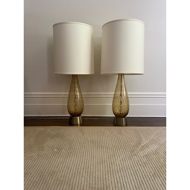 The lamps feature elegant hand-blown teardrop forms in richly toned amber Murano glass with subtle internal movement and...