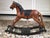 A vintage carved wooden brown painted rocking horse with a black painted mane, natural horsehair tail, tooled leather...