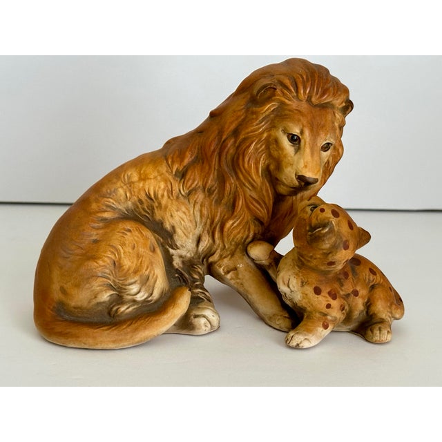Vintage hand-painted ceramic or porcelain figurine of a male lion with a spotted cub. Possibly dating from the...