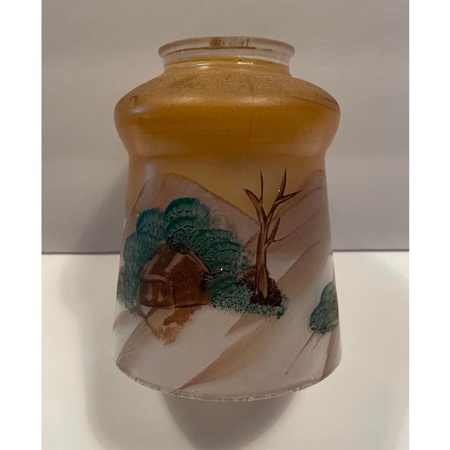 A 1930s hand painted glass ceiling light shade with a country scene of trees, hills and cabins. Unsigned. The width of the...