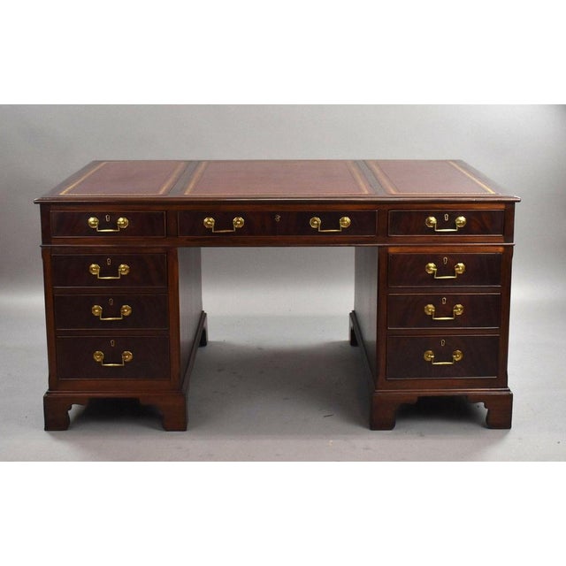 Edwardian pedestal desk, crafted in richly figured mahogany . The rectangular top is inset with a burgundy leather writing...