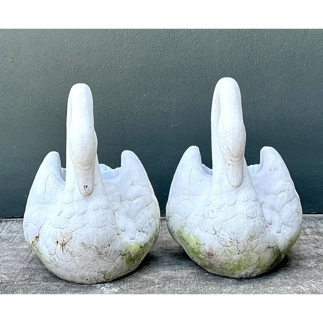 This pair of vintage cast concrete swan planters is a graceful study in garden sculpture, modeled in a soft, chalky white...