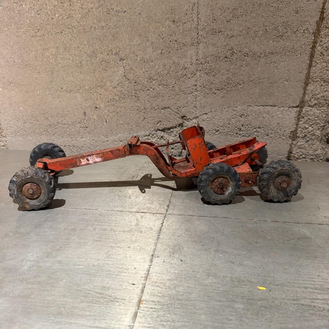 For your consideration, a vintage 1940s–1950s Structo pressed steel orange road grader toy, featuring a long metal frame...
