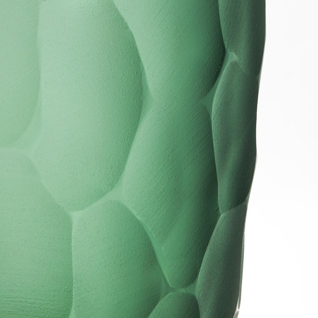 The Murano Battuto Vase in Emerald Green, size small, is a masterpiece of artistry and technique, realized through the...