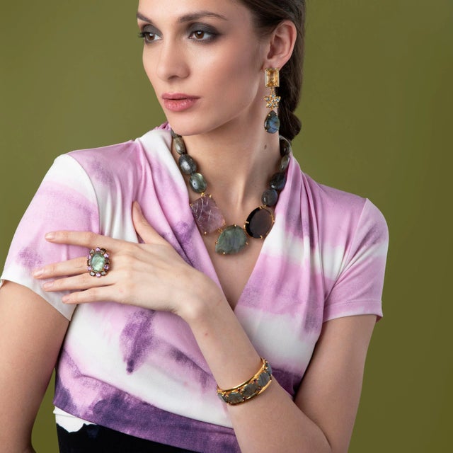 The Gabrielle Ring showcases an exquisite oval stone encircled by a halo of contrasting stones, offering both timeless...