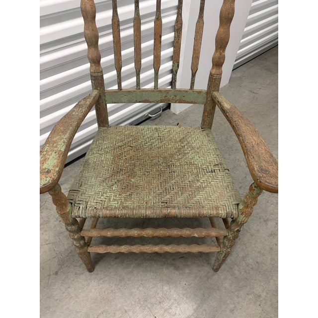 Charming vintage American Primitive-style armchair featuring a tall spindle back, turned posts and stretchers, sculpted...