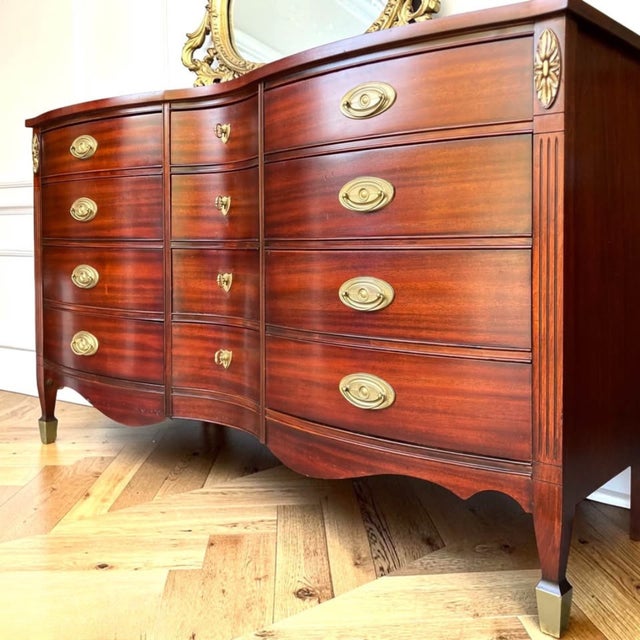 This vintage Federal-style mahogany dresser by Dixie Furniture features a graceful serpentine front, reeded corner...