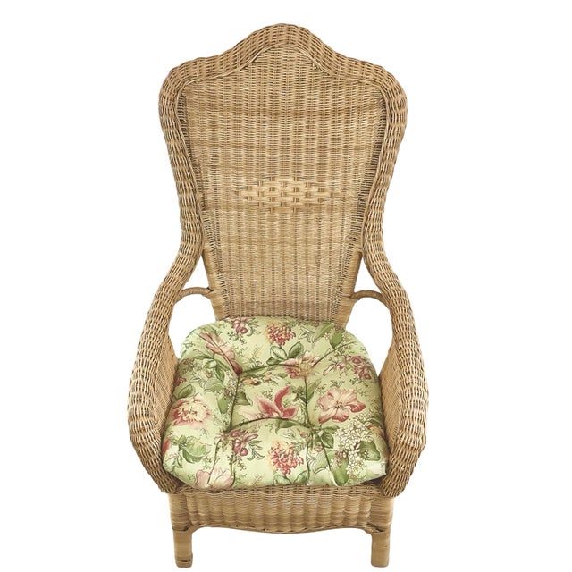 Vintage high-back wicker and rattan armchair featuring a sculptural shaped back, woven arms, and removable floral seat...