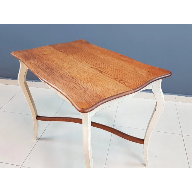 This is a Louis XV style midsize two-tone shabby chic wood side entry occasional table from France. Raised on gorgeous,...