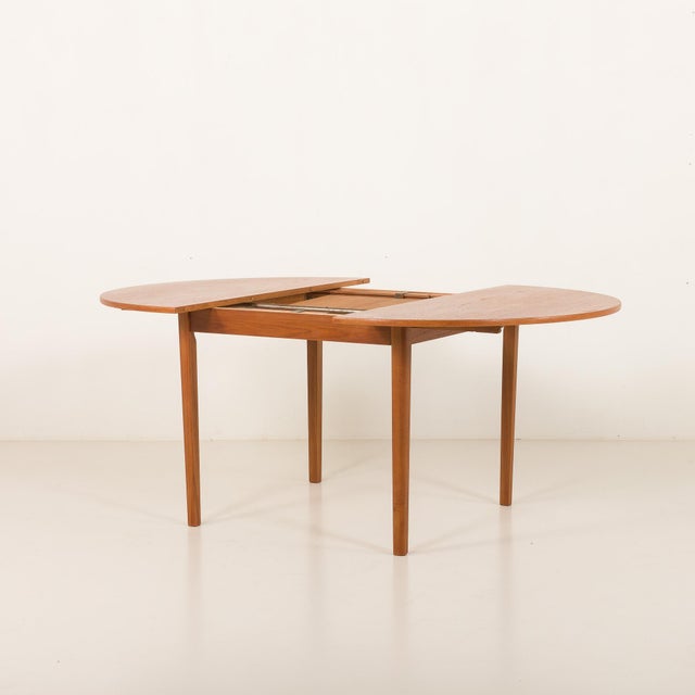 Danish vintage mid-century round teak extension table. It features one collapsing additional leaf, that hides under the...