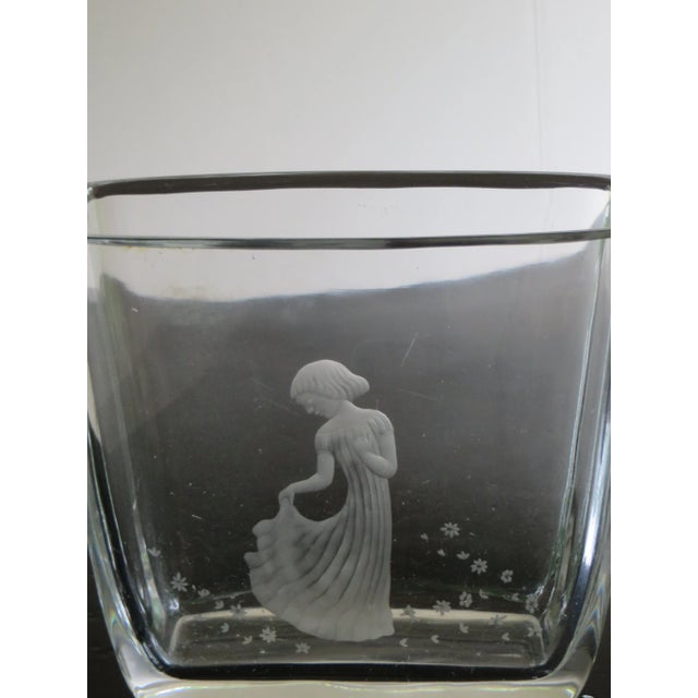 This art glass vase is clear with an etched and frosted girl surrounded by flowers on one side. It was made by Orrefors in...