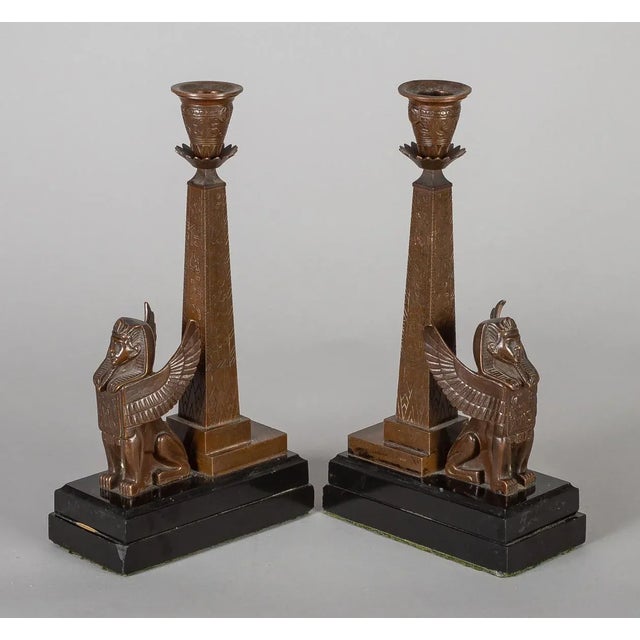 Pair of bronze Egyptian Revival candlesticks with winged sphinx sitting before an obelisk inscribed with hieroglyphics,...