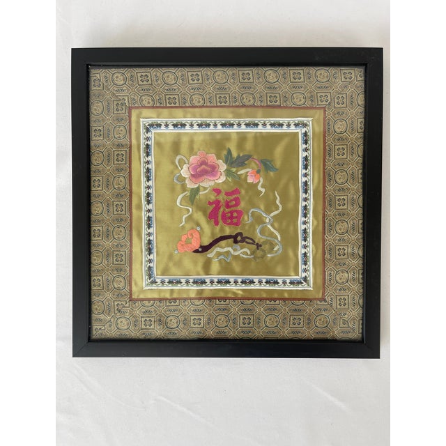 Pair of Chinese silk embroidered gold silk panels with floral and bird motifs. Woven silk borders frame the panels within...