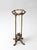 Antique cast iron plant stand with a tall, narrow profile featuring twisted uprights, an ornate scrolled base, and a...