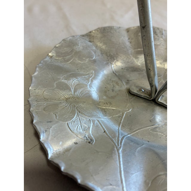 A charming vintage hand wrought aluminum tray, featuring a scalloped hammered edge, embossed floral detailing, and a...