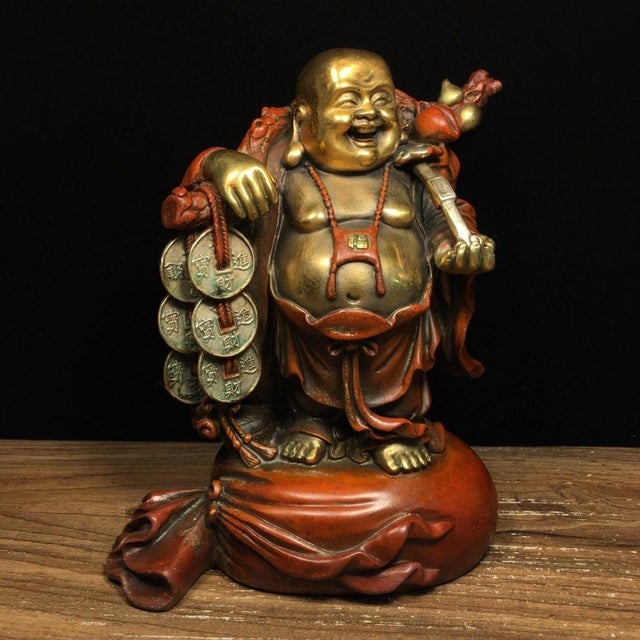 A charming vintage cast bronze sculpture depicting the laughing Buddha, finished with partial gilding and rich red patina....