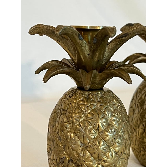 Transform your space with this stunning pair of Hollywood Regency-style brass pineapple candlestick holders, a true...